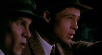 Movie still from “A River Runs Through It” (1992), directed by Robert Redford – A man in a suit and a hat is sitting next to another man in a suit; Close Up shot, Over the shoulder angle