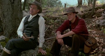 Movie still from “A River Runs Through It” (1992), directed by Robert Redford – A man and a boy sitting on the ground in the woods; Medium shot, Low angle