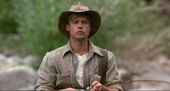 Movie still from “A River Runs Through It” (1992), directed by Robert Redford – A man in a hat and a jacket holding a stick; Medium shot, Low angle