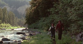 Movie still from “A River Runs Through It” (1992), directed by Robert Redford – A couple of people that are walking in the grass; Wide shot, Low angle