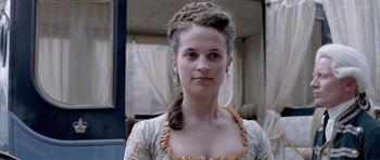 Movie still from “A Royal Affair” (2012), directed by Nikolaj Arcel – A young woman in a white and yellow dress; Close Up shot, Over the shoulder angle