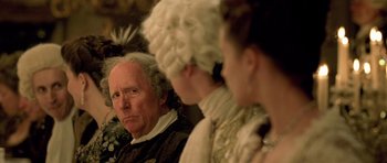 Movie still from “A Royal Affair” (2012), directed by Nikolaj Arcel – An old man and two women dressed in period costumes; Close Up shot, Over the shoulder angle
