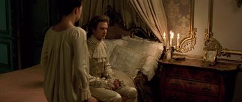 Movie still from “A Royal Affair” (2012), directed by Nikolaj Arcel – A man and a woman sitting on a bed in front of candles; Medium shot, High angle