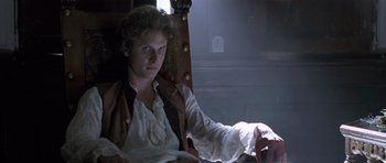 Movie still from “A Royal Affair” (2012), directed by Nikolaj Arcel – A man sitting in a chair wearing a white shirt; Medium shot, Low angle