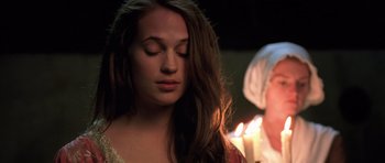 Movie still from “A Royal Affair” (2012), directed by Nikolaj Arcel – A woman with her eyes closed is holding a lit candle; Close Up shot, Over the shoulder angle