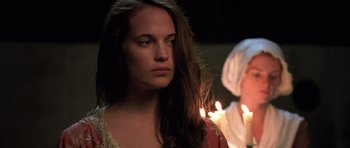 Movie still from “A Royal Affair” (2012), directed by Nikolaj Arcel – A woman standing in front of a lit candle; Close Up shot, Over the shoulder angle