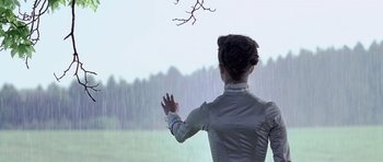 Movie still from “A Royal Affair” (2012), directed by Nikolaj Arcel – A woman standing in front of a window in the rain; Medium shot, Over the shoulder angle