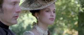 Movie still from “A Royal Affair” (2012), directed by Nikolaj Arcel – A young woman wearing a hat and a dress; Close Up shot, Low angle