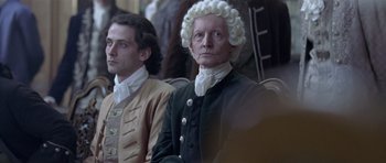 Movie still from “A Royal Affair” (2012), directed by Nikolaj Arcel – A man in a wig sitting next to another man in a wig; Medium shot, High angle