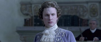 Movie still from “A Royal Affair” (2012), directed by Nikolaj Arcel – A man in a purple dress with a white lace collar; Close Up shot, Low angle