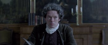 Movie still from “A Royal Affair” (2012), directed by Nikolaj Arcel – An older man in a brown jacket and a white beard; Close Up shot, Over the shoulder angle