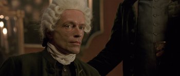 Movie still from “A Royal Affair” (2012), directed by Nikolaj Arcel – A man in a wig and wig stands next to another man; Close Up shot, Over the shoulder angle