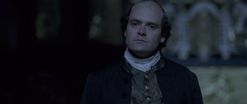 Movie still from “A Royal Affair” (2012), directed by Nikolaj Arcel – A man in a black jacket and a white shirt; Close Up shot, Over the shoulder angle