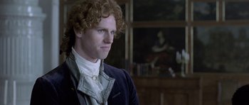 Movie still from “A Royal Affair” (2012), directed by Nikolaj Arcel – A man with curly red hair wearing a suit and tie; Close Up shot, Over the shoulder angle