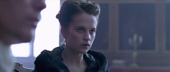Movie still from “A Royal Affair” (2012), directed by Nikolaj Arcel – A young woman in a fur coat looking at the camera; Close Up shot, Over the shoulder angle