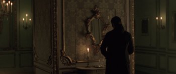 Movie still from “A Royal Affair” (2012), directed by Nikolaj Arcel – A man standing in front of a mirror with a lit candle; Medium shot, Over the shoulder angle