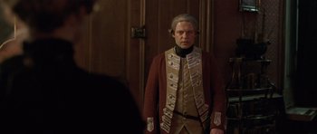Movie still from “A Royal Affair” (2012), directed by Nikolaj Arcel – A man dressed in a military uniform standing in front of a door; Medium shot, Over the shoulder angle