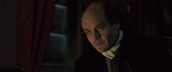 Movie still from “A Royal Affair” (2012), directed by Nikolaj Arcel – A man in a black suit and a white shirt; Close Up shot, Over the shoulder angle