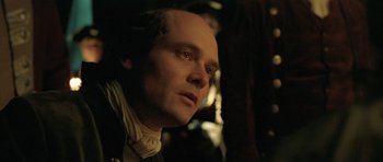 Movie still from “A Royal Affair” (2012), directed by Nikolaj Arcel – A person wearing a suit and tie; Close Up shot, Over the shoulder angle