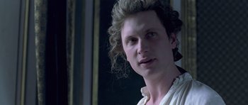 Movie still from “A Royal Affair” (2012), directed by Nikolaj Arcel – A young man with curly blonde hair wearing a white shirt; Close Up shot, Over the shoulder angle