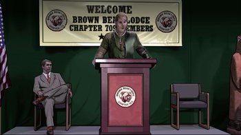 Movie still from “A Scanner Darkly” (2006), directed by Richard Linklater – A man standing at a podium in front of a group of people; Wide shot, High angle