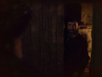 Movie still from “A Serious Man” (2009), directed by Joel Coen – A man standing next to a wooden door; Medium shot, Over the shoulder angle