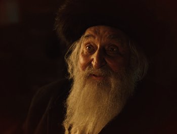 Movie still from “A Serious Man” (2009), directed by Joel Coen – An old man with a long beard wearing a hat; Close Up shot, Low angle