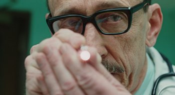 Movie still from “A Serious Man” (2009), directed by Joel Coen – An older man with glasses is holding a cigarette; Extreme Close Up shot, Over the shoulder angle