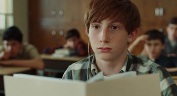 Movie still from “A Serious Man” (2009), directed by Joel Coen – A young man sitting in front of an open book; Close Up shot, Over the shoulder angle