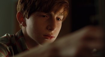 Movie still from “A Serious Man” (2009), directed by Joel Coen – A young man looking at a tablet computer screen; Close Up shot, Over the shoulder angle