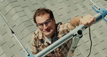 Movie still from “A Serious Man” (2009), directed by Joel Coen – A man with glasses and a plaid shirt is on the roof of a house; Close Up shot, Overhead angle