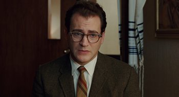 Movie still from “A Serious Man” (2009), directed by Joel Coen – A person wearing a suit and tie; Close Up shot, Over the shoulder angle