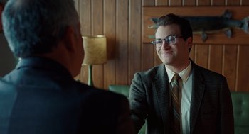 Movie still from “A Serious Man” (2009), directed by Joel Coen – A man wearing a suit and tie talking to another man; Medium shot, Over the shoulder angle
