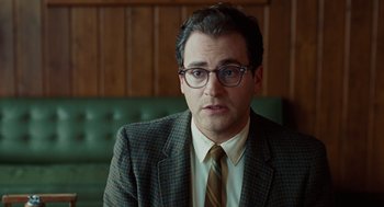 Movie still from “A Serious Man” (2009), directed by Joel Coen – A man in a suit and tie sitting in a chair; Close Up shot, Over the shoulder angle