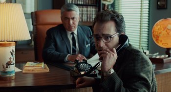 Movie still from “A Serious Man” (2009), directed by Joel Coen – Two men sitting at a table with a phone in their hands; Medium shot, Over the shoulder angle