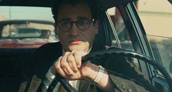 Movie still from “A Serious Man” (2009), directed by Joel Coen – A man driving a car in the street with his hands on the steering wheel; Close Up shot, Over the shoulder angle