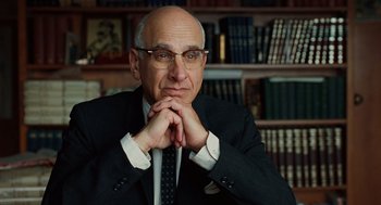 Movie still from “A Serious Man” (2009), directed by Joel Coen – A man in a suit and tie sitting in front of a book shelf; Close Up shot, Over the shoulder angle