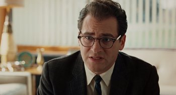 Movie still from “A Serious Man” (2009), directed by Joel Coen – A person wearing a suit and glasses; Close Up shot, Over the shoulder angle