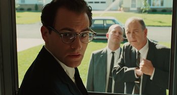 Movie still from “A Serious Man” (2009), directed by Joel Coen – A group of men standing next to each other in front of a car; Medium shot, Low angle