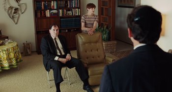 Movie still from “A Serious Man” (2009), directed by Joel Coen – Two men in suits sitting in a living room; Medium shot, Over the shoulder angle