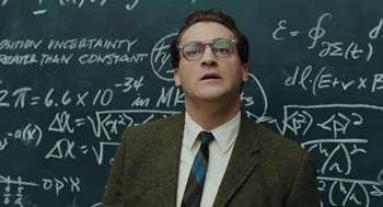 Movie still from “A Serious Man” (2009), directed by Joel Coen – A man wearing a suit and tie standing in front of a chalkboard; Medium shot, Low angle