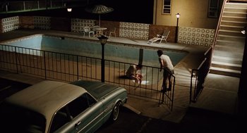 Movie still from “A Serious Man” (2009), directed by Joel Coen – A man and a woman in front of a swimming pool at night; Extreme Wide shot, High angle