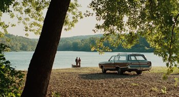 Movie still from “A Serious Man” (2009), directed by Joel Coen – Two people standing on the shore of a body of water; Extreme Wide shot, High angle