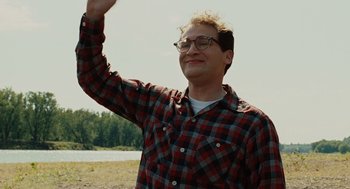 Movie still from “A Serious Man” (2009), directed by Joel Coen – A man in a red and black plaid shirt waving; Medium shot, Low angle