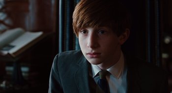 Movie still from “A Serious Man” (2009), directed by Joel Coen – A young man in a suit and tie looking into the distance; Close Up shot, Over the shoulder angle