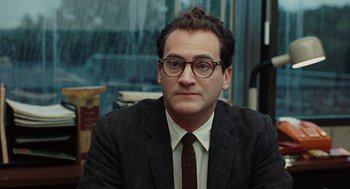 Movie still from “A Serious Man” (2009), directed by Joel Coen – A man in a suit and tie sitting in front of a window; Close Up shot, Over the shoulder angle