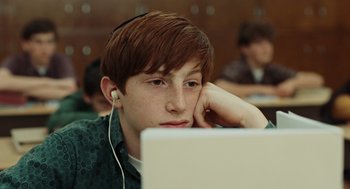 Movie still from “A Serious Man” (2009), directed by Joel Coen – A young man with headphones looking at a laptop screen; Close Up shot, Over the shoulder angle