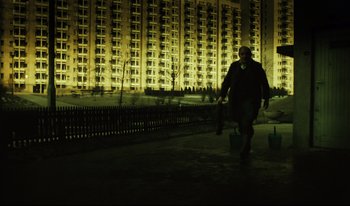 Movie still from “A Short Film About Killing” (1988), directed by Krzysztof Kieslowski – A man walking down the street in front of tall buildings; Wide shot, Low angle