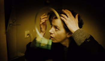 Movie still from “A Short Film About Killing” (1988), directed by Krzysztof Kieslowski – A woman looking into a mirror while holding her hair; Close Up shot, High angle