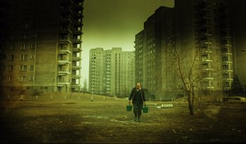 Movie still from “A Short Film About Killing” (1988), directed by Krzysztof Kieslowski – A man walking across a field holding two green boxes; Wide shot, Low angle